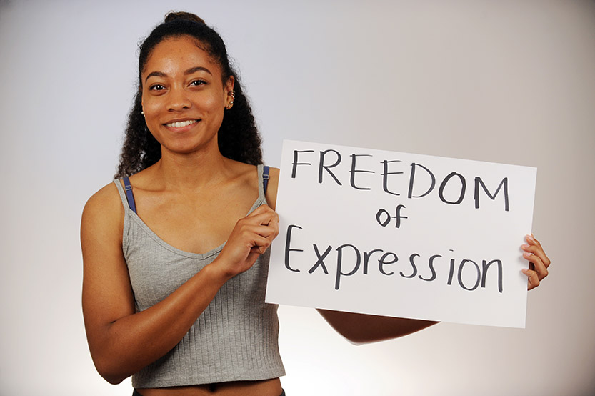 A woman holds up a sign which says: Freedom of Expression