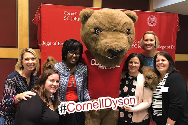 A group of faculty stand together with the Cornell Bear
