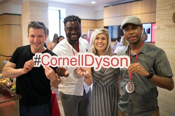 Alumni smile holding a #CornellDyson sign
