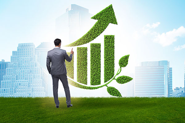 Green economy growth concept with businessman standing in front of a rising bar chart made of green foliage