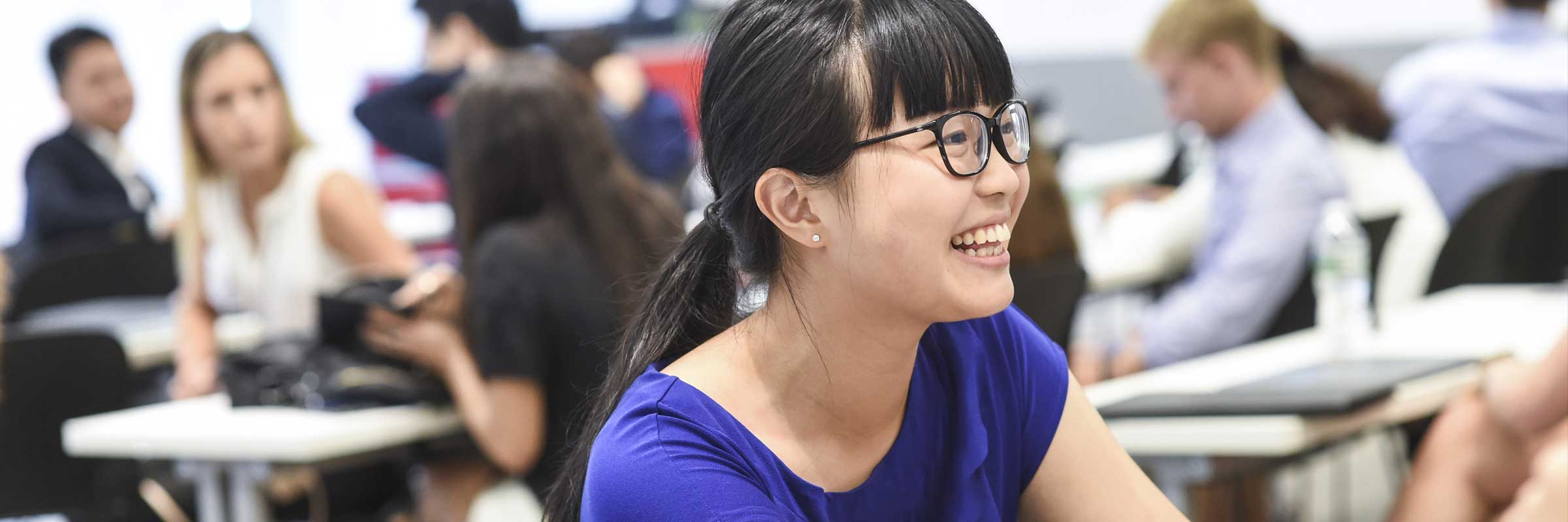 A female student sitting in class smiling.