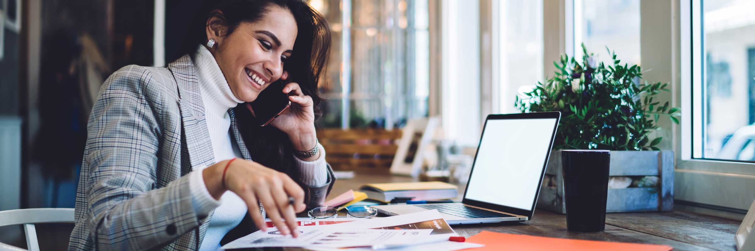 Woman smiling on the phone while working at a desk.
