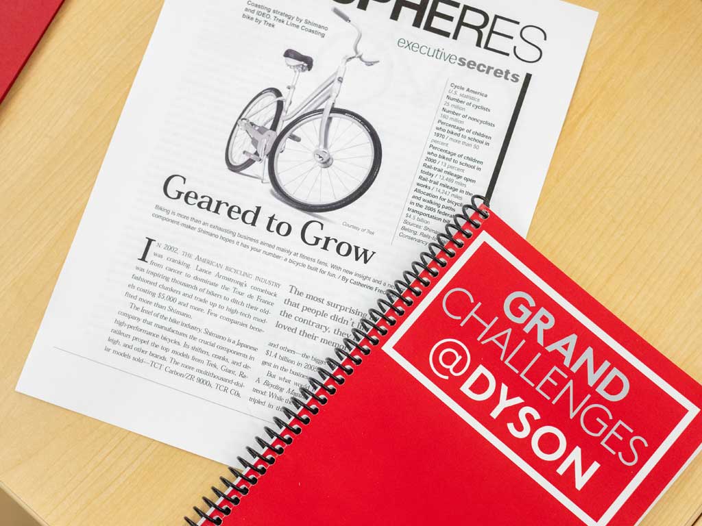 Dyson Grand Challenges notebook and newspaper laying on a desk.