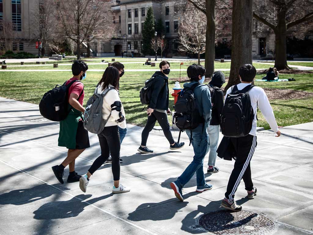Students in facemasks walk in the quad.