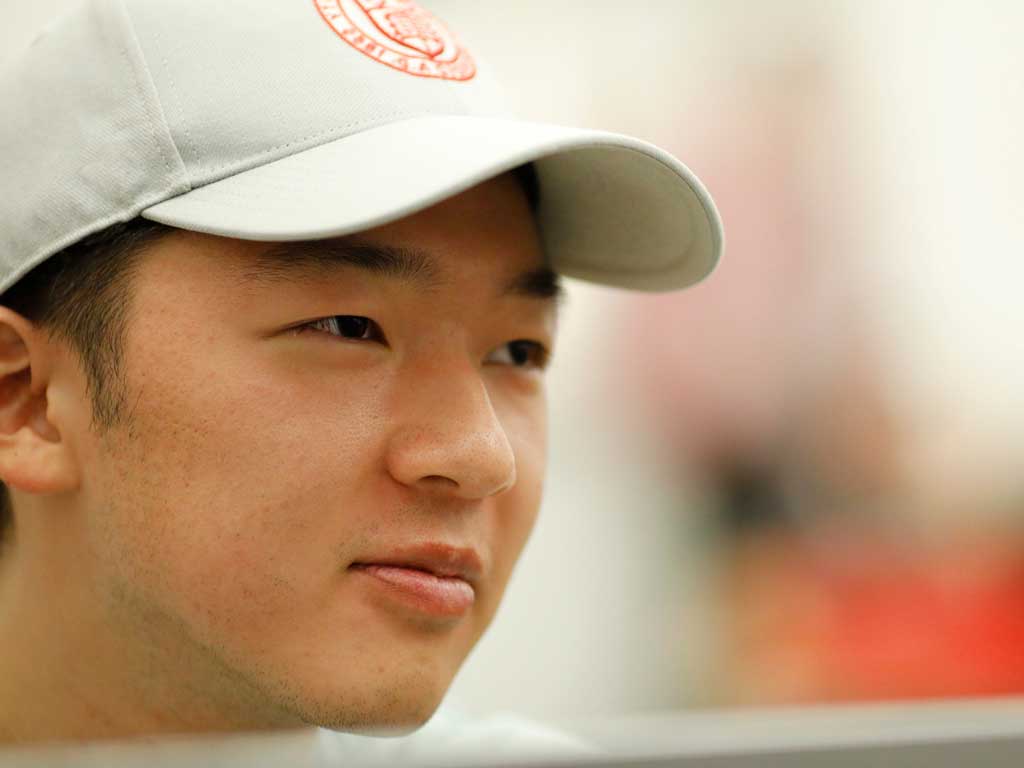 A person wearing a tan baseball hat with the red Cornell University seal on it.