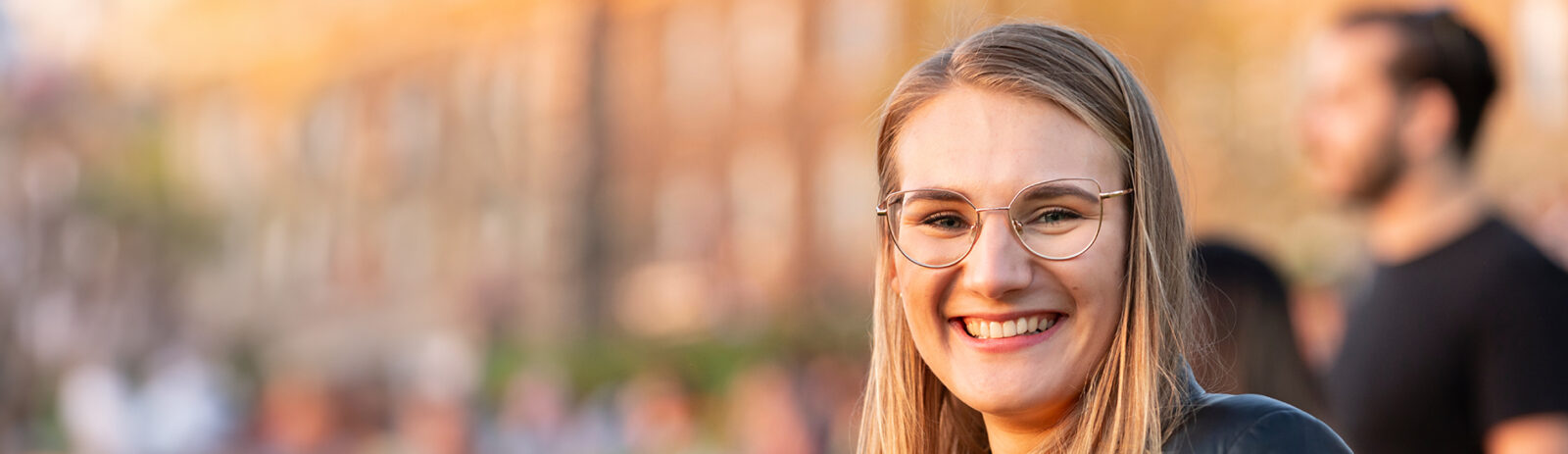 A blond woman wearing glasses smiles at the camera.
