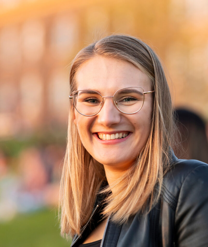 A blonde woman wearing glasses smiling at the camera.