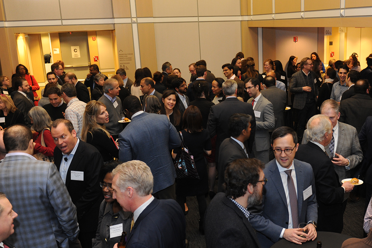 People in business attire network in a large open room.