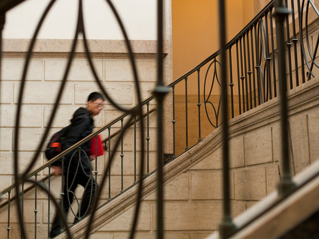A student walks up the main staircase inside Warren Hall.