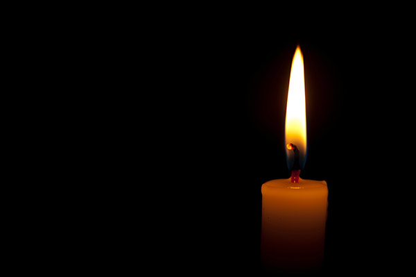 photo of a burning candle on a dark background.