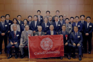 The Japan Food Executives hold a red Cornell banner and pose for the camera