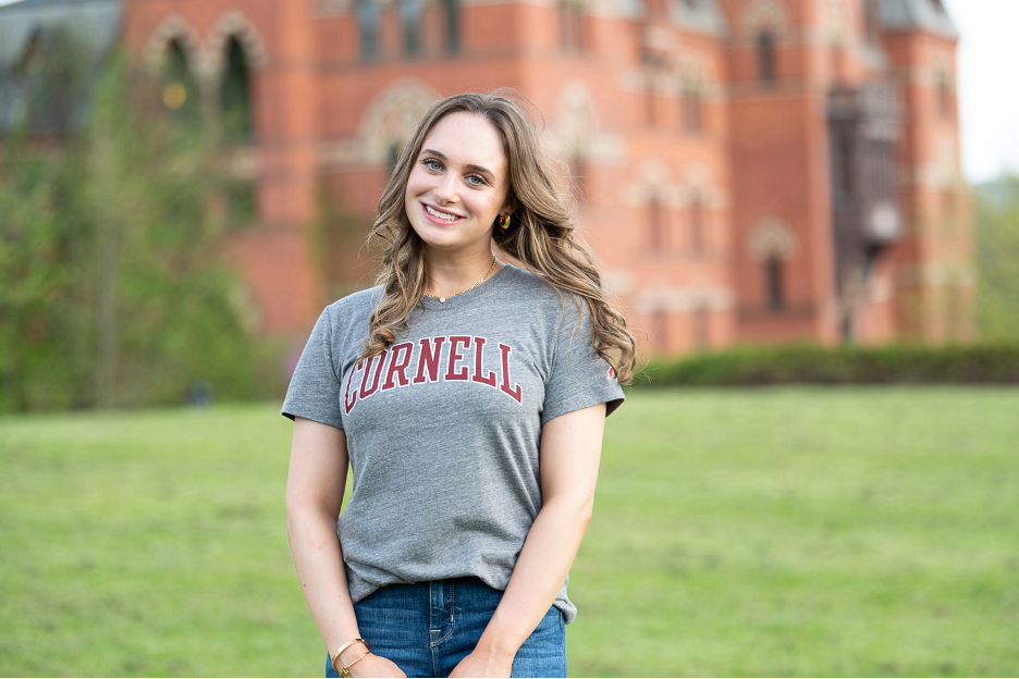 Photo of Carly Chasen wearing a gray Cornell t-shirt and standing in front of Sage Hall.