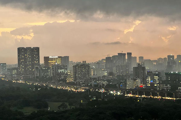 photo of a large city filled with tall buildings and a busy highway, taken in the evening and showing lights in the buildings and traffic-filled highway.