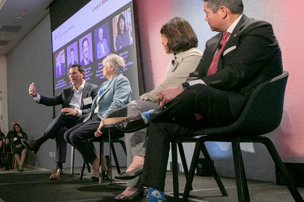 Photo of four panelists on stage at the Cornell Business Forum