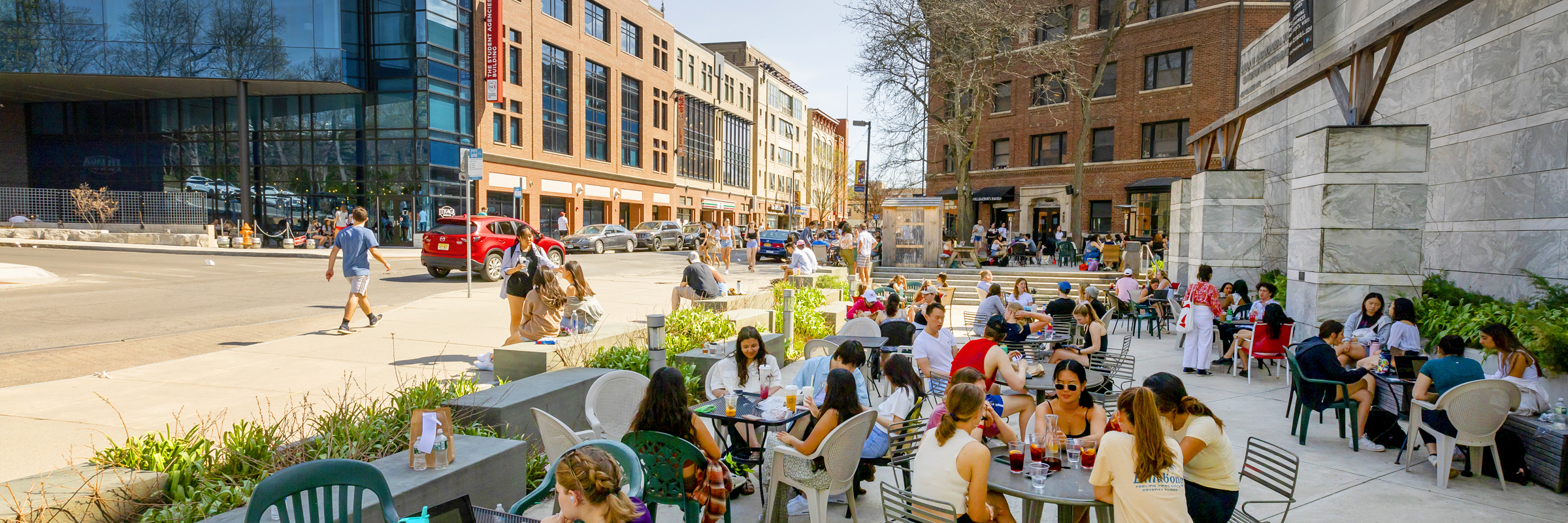 People sitting at outdoor dining tables in Collegetown.