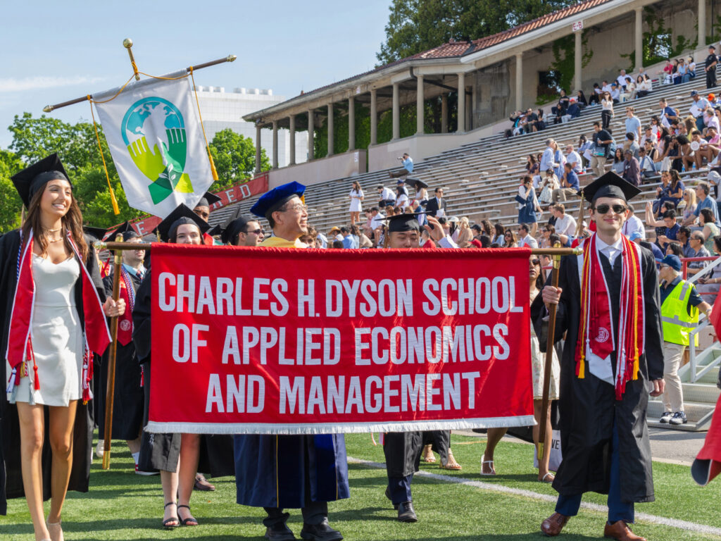 Image of Dean Zhou processing with the Charles H. Dyson School of Applied Economics and Management banner and graduates