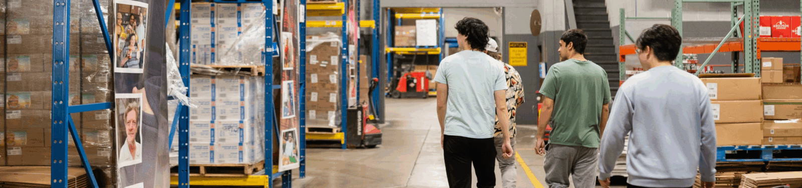 Four people walk in a warehouse.